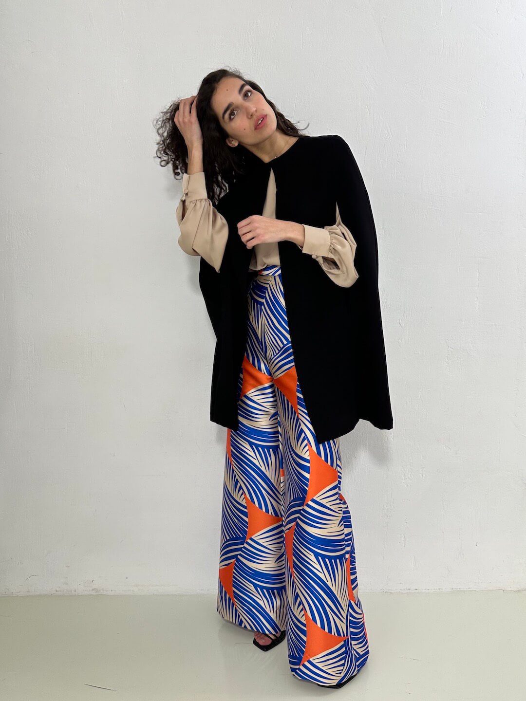 vista delantera en modelo de capa corta negra con caída fluida y corte clásico. Combinada con blusa OREGON y pantalón NAGANO – dearroyo studio